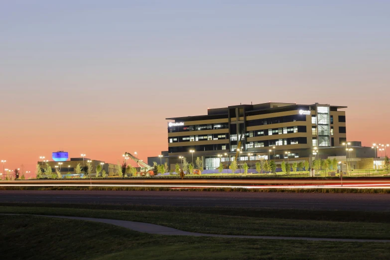 a very tall building sitting on the side of a road, at twilight, medical research facility, landscape wide shot, jets