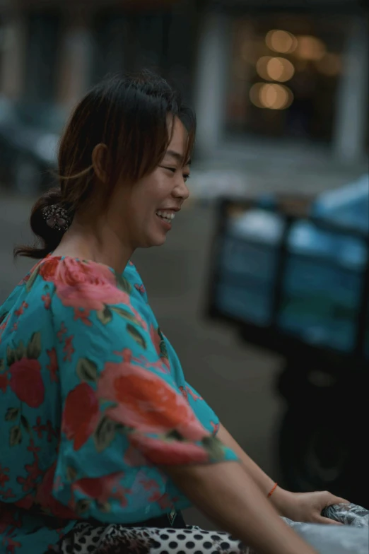 a woman sitting on a bench using a laptop computer, inspired by Cui Bai, happening, standing in a city street, cinestill colour cinematography, wearing floral chiton, smiling playfully