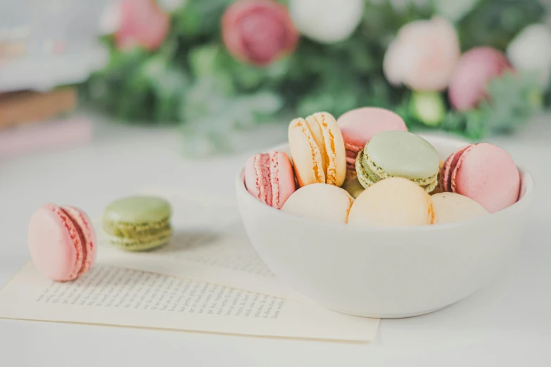 a bowl of macarons sitting on top of a table, by Nicolette Macnamara, pexels contest winner, pink white and green, reading, full product shot, multiple stories