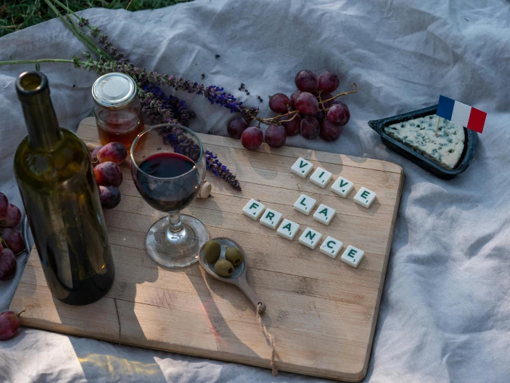 a bottle of wine sitting on top of a wooden cutting board, inspired by Louis Stettner, pexels contest winner, picnic, funny jumbled letters, square, love scene