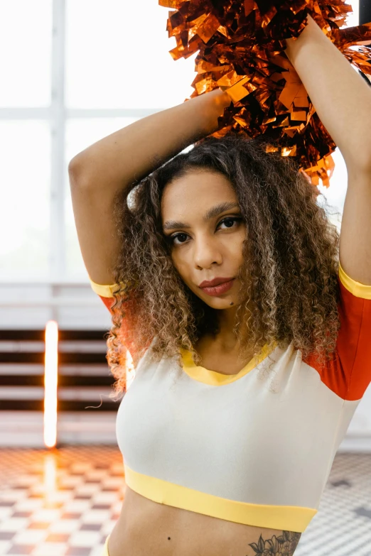 a beautiful young woman holding a pom pom, trending on pexels, black arts movement, white and orange breastplate, wearing a volleyball jersey, wavy hair spread out, nonbinary model