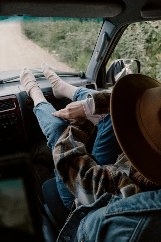 a man sitting in the driver's seat of a car, by Jessie Algie, trending on pexels, renaissance, wearing kneesocks, couple, wearing a cowboy hat, laying down