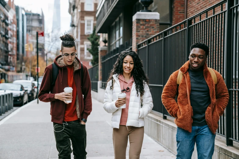 a group of people walking down a sidewalk, trending on pexels, brown skinned, student, three, cozy