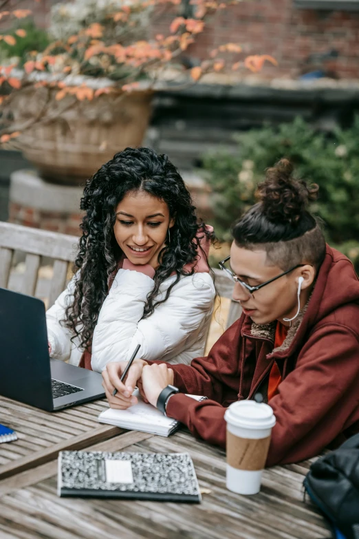 a couple of people sitting at a table with laptops, trending on pexels, renaissance, college girls, hispanic, lesbian, in a city park