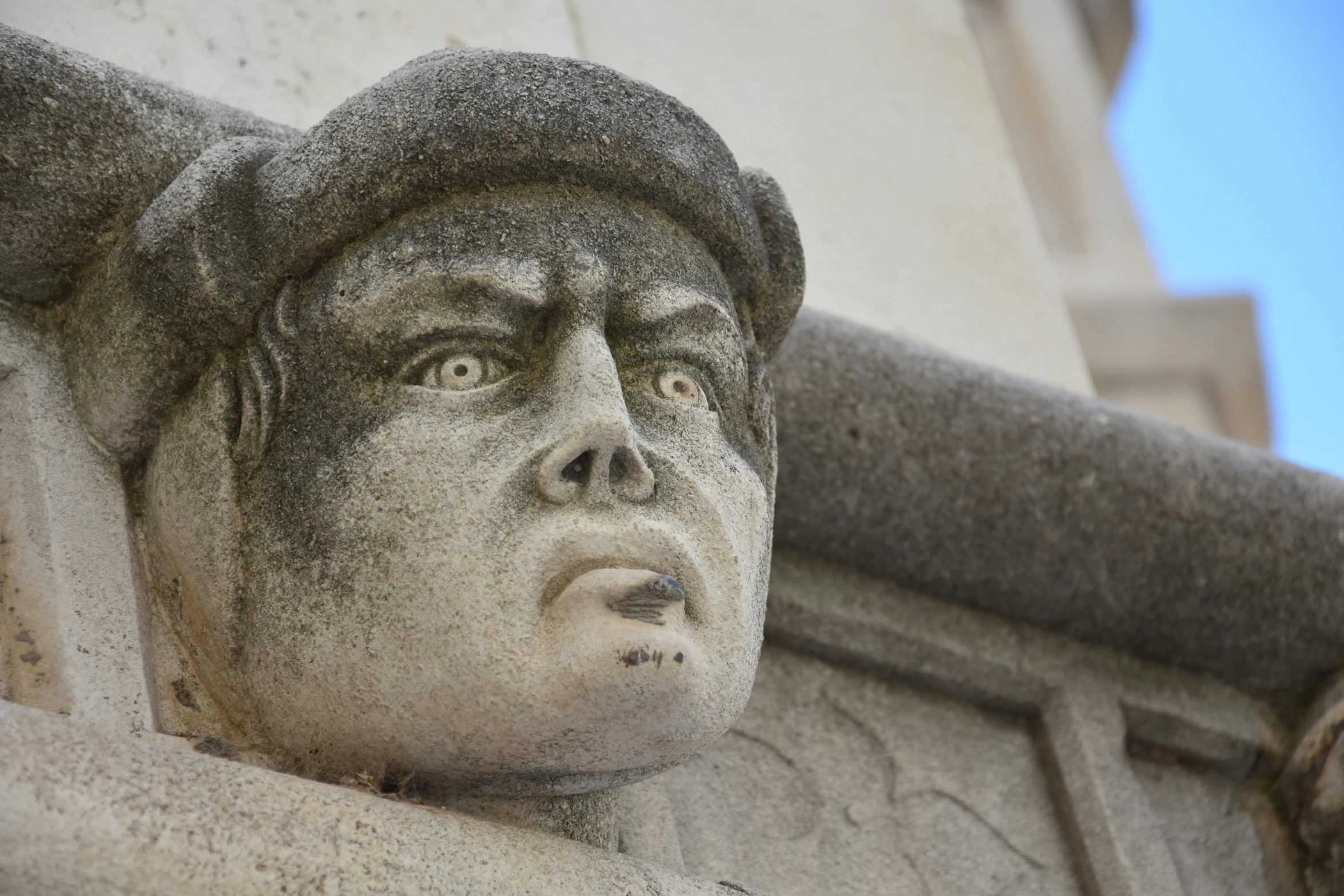 a statue of a man on the side of a building, inspired by Taddeo Gaddi, art nouveau, pointed face and grey eyes, angry frown, very detailed faces, square face