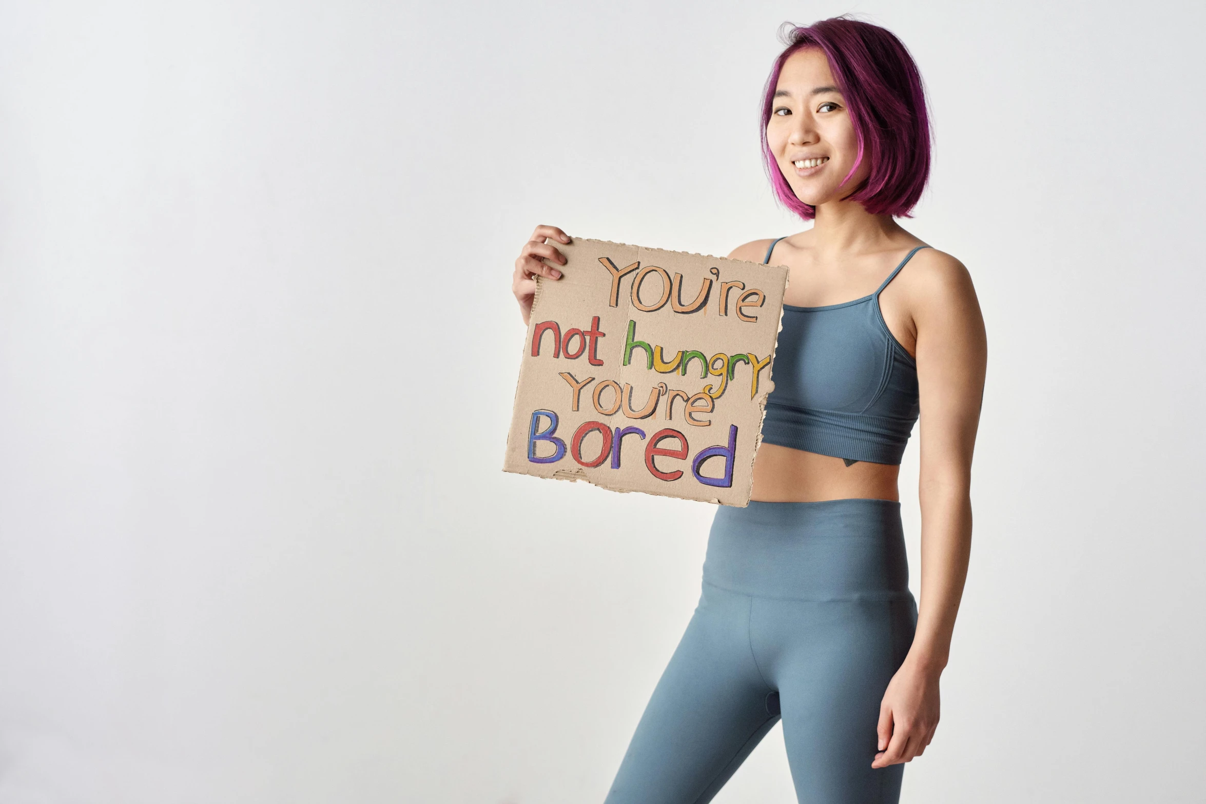 a woman in a sports bra top holding a sign, inspired by helen huang, trending on pexels, muted colored bodysuit, are bure boke, boring, brightly coloured