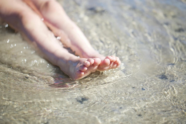 a close up of a person's feet in the water, unsplash, seaside, manly, family friendly, crystal clear water