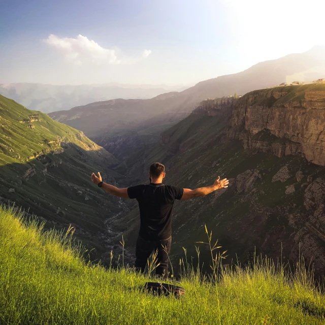 a man standing on top of a lush green hillside, pexels contest winner, les nabis, assyrian, praising the sun, canyons, praying