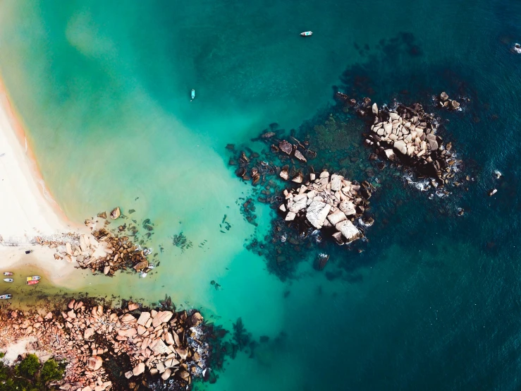 a large body of water next to a sandy beach, pexels contest winner, birds eye overhead perspective, rock pools, glowing hue of teal, helicopter view