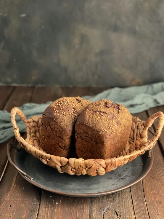 a basket of bread sitting on top of a wooden table, black and terracotta, thumbnail, frontal shot, two