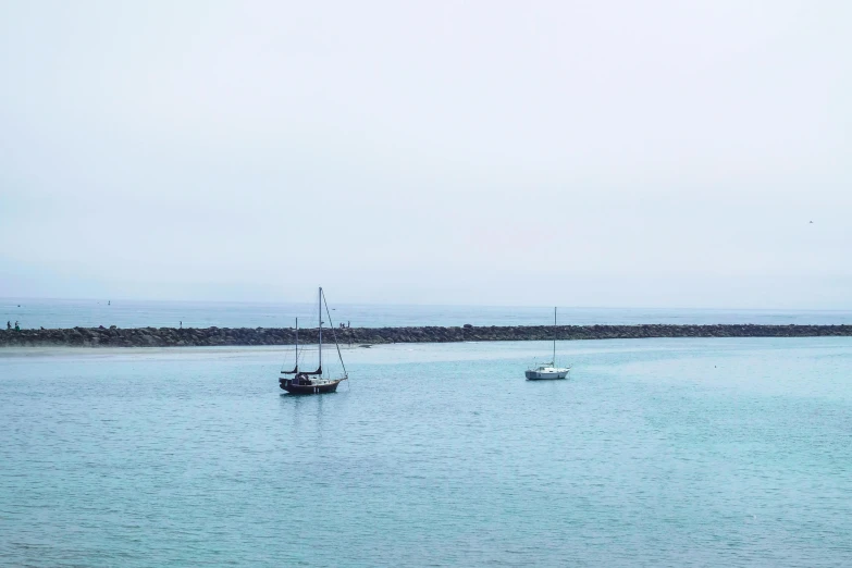 a couple of boats floating on top of a body of water, by Peter Churcher, pexels contest winner, minimalism, hollister ranch, cyan mist, set sail, panoramic