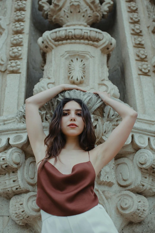 a woman posing for a picture in front of a building, an album cover, inspired by Elsa Bleda, pexels contest winner, art nouveau, madison beer girl portrait, in an ancient altar, fair olive skin, maroon