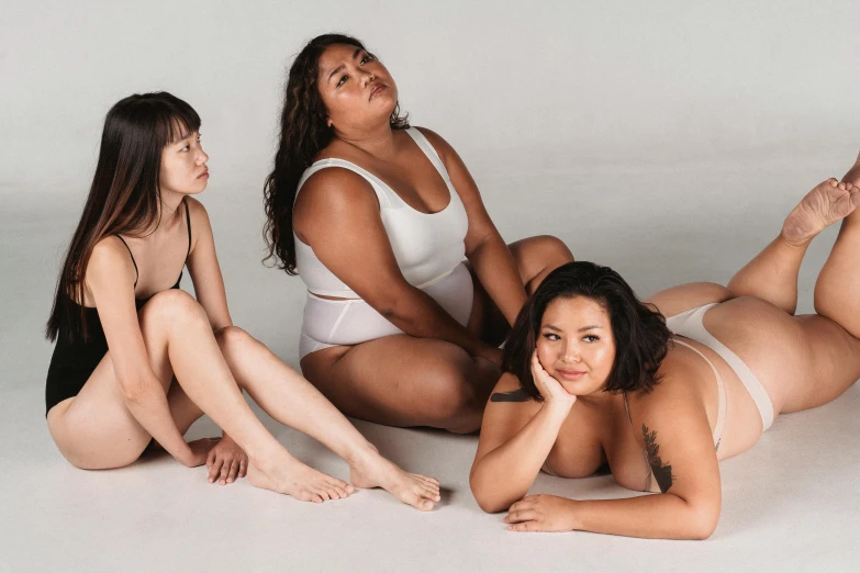 a group of women sitting on top of a white floor, thick body, half asian, rubenesque, upper body image