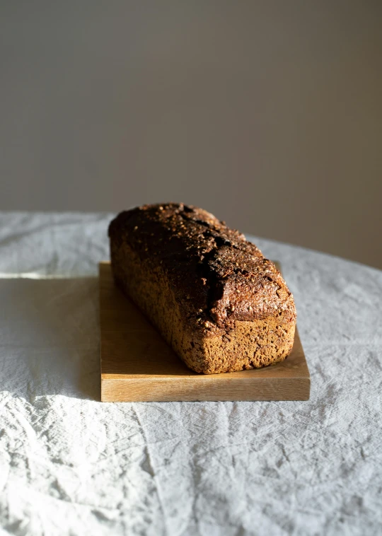 a loaf of bread sitting on top of a cutting board, by Vadym Meller, hurufiyya, dark brown, hammershøi, “ iron bark, panorama
