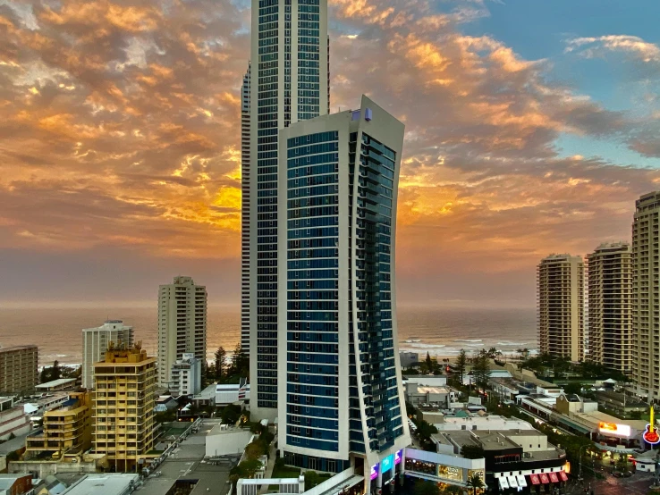 a tall building sitting in the middle of a city, gold coast australia, hotel room, evening sunset, “the ultimate gigachad