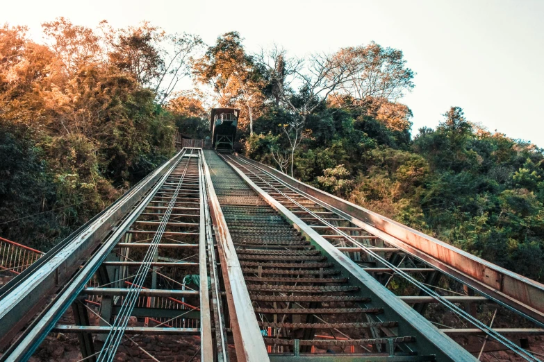 a train going down a track with trees in the background, an album cover, by Alejandro Obregón, pexels contest winner, sumatraism, stairway, chairlifts, built on a steep hill, são paulo