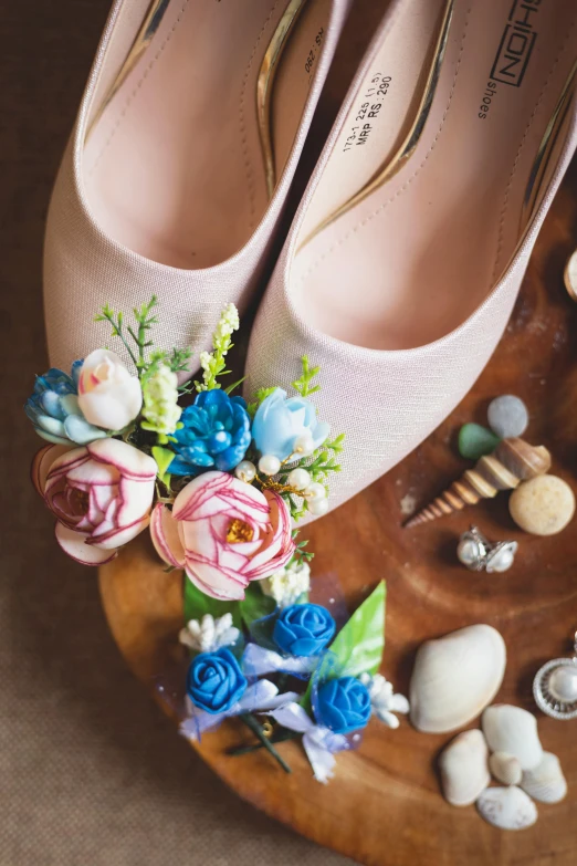 a pair of shoes sitting on top of a wooden tray, floating bouquets, shells, jewels, blue and pink accents