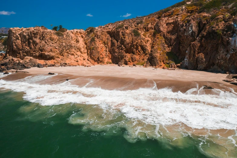 a man riding a surfboard on top of a sandy beach, a tilt shift photo, pexels contest winner, les nabis, steep cliffs, thumbnail, portugal, on a hot australian day