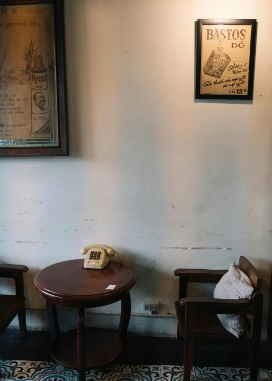 a phone sitting on top of a wooden table, a portrait, by Yasushi Sugiyama, private press, cafe interior, old chairs, jakarta, wall ]