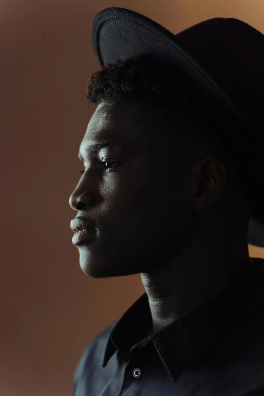 a close up of a person wearing a hat, by James Morris, black teenage boy, profile posing, soft light, ignant