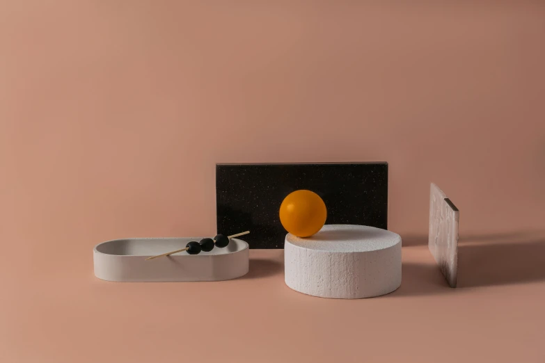 a couple of bowls sitting on top of a table, a still life, inspired by Bauhaus, minimalism, carved marble, rectangle, grey orange, circle