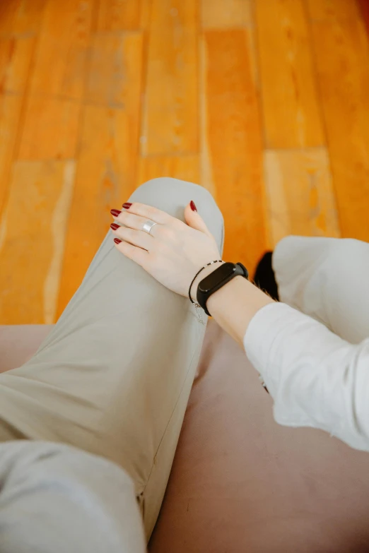 a woman sitting on top of a couch next to a wooden floor, by Nina Hamnett, trending on pexels, holding hands, wearing elegant casual clothes, 15081959 21121991 01012000 4k, jewelry