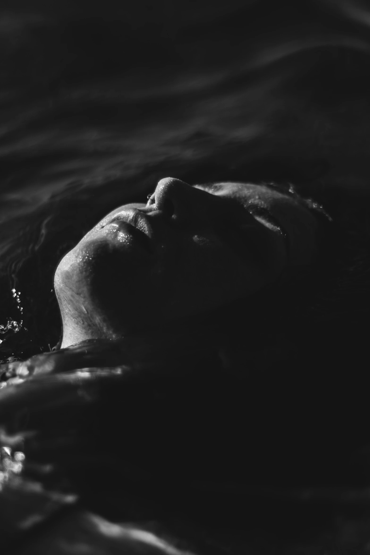 a black and white photo of a woman floating in the water, inspired by Max Dupain, unsplash, dark face, asleep, carnal ) wet, summer night