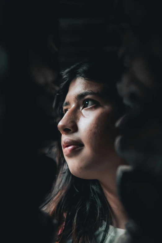 a woman looking off into the distance in a dark room, by Alejandro Obregón, hurufiyya, looking up at the camera, promo image, multiple stories, young himalayan woman