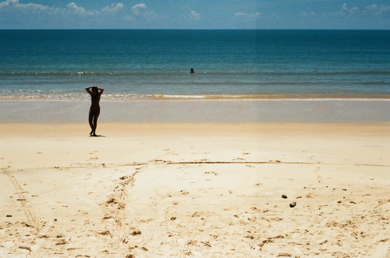 a man standing on top of a sandy beach next to the ocean, by Nina Hamnett, unsplash contest winner, minimalism, on a hot australian day, omaha beach, mermaids in distance, at a tropical beach