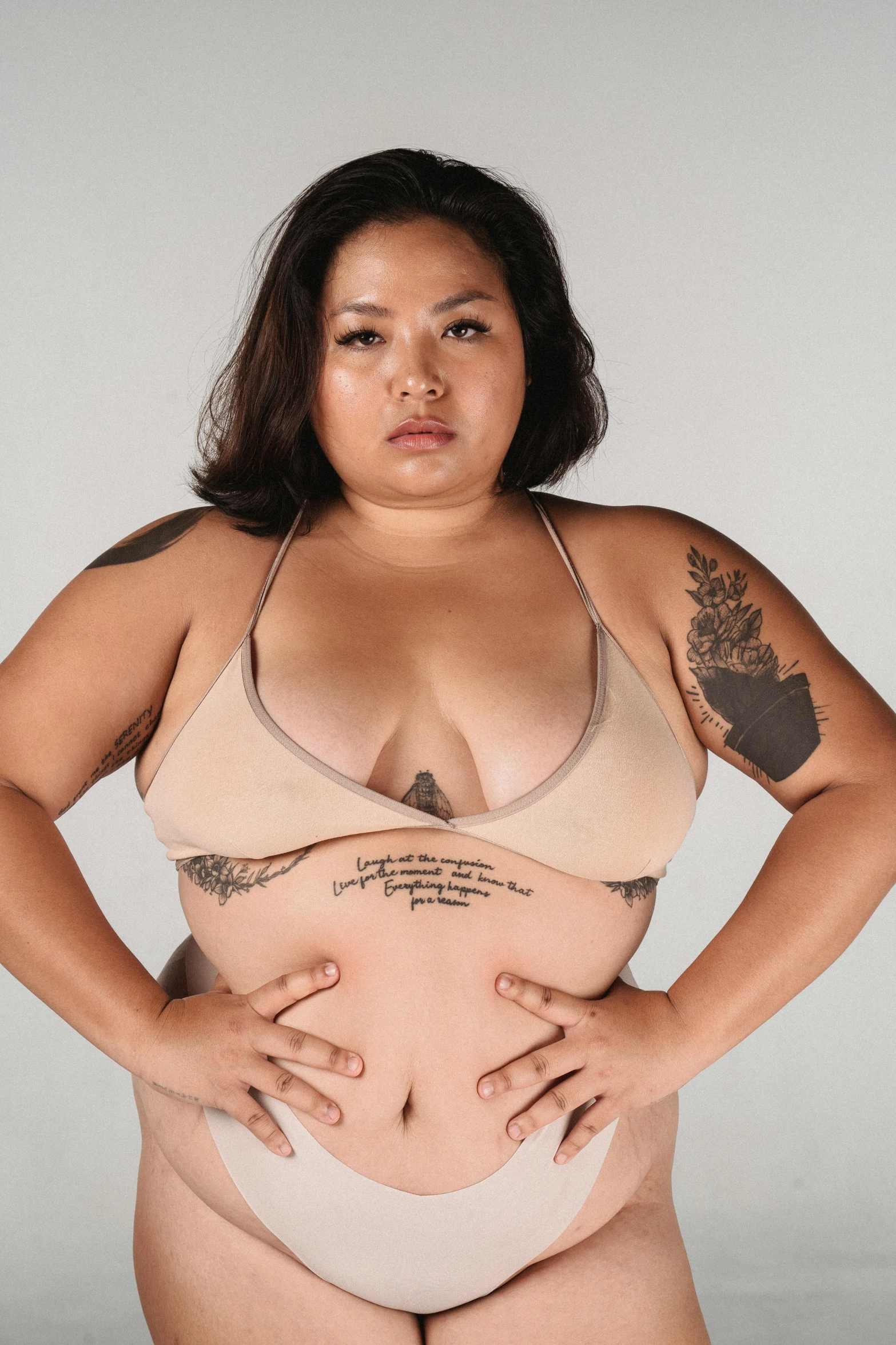 a woman in a bikini posing for a picture, a tattoo, inspired by Ruth Jên, an overweight, wearing bra, promo photo, her skin is light brown