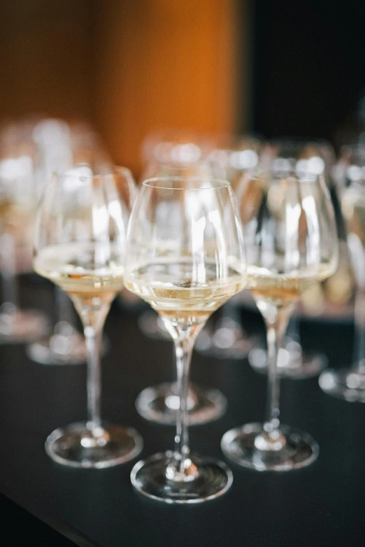 a bunch of wine glasses sitting on top of a table, white and gold robes, medium distance shot, in a row, performing