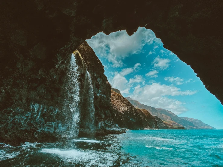 a waterfall coming out of a cave into the ocean, by Daniel Lieske, pexels contest winner, reunion island, farming, 4 k smooth, an archway