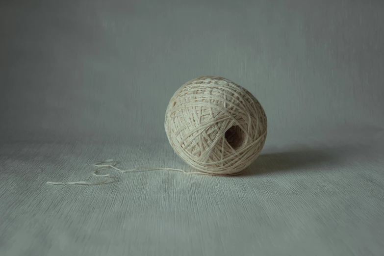 a ball of yarn sitting on top of a table, inspired by Agnes Martin, unsplash, hyperrealism, studio medium format photograph, eggshell color, ignant, alessio albi