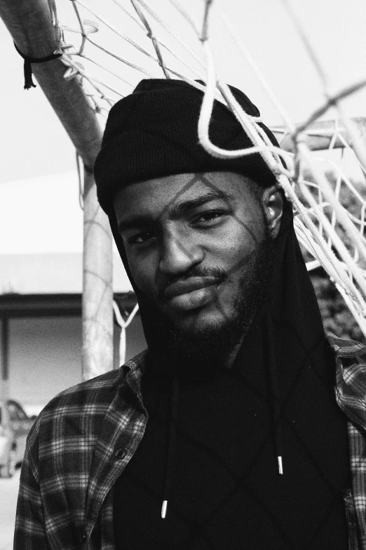 a black and white photo of a man standing in front of a net, inspired by Paul Georges, wearing a bandana and chain, frank ocean, giddy smirk, jaylen brown