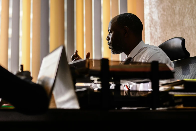 a man sitting at a desk in front of a laptop computer, a photo, by Bernard Meninsky, pexels contest winner, hurufiyya, sitting in dean's office, profile image, still cinematic, george pemba