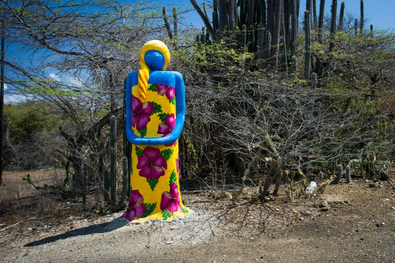 a colorful statue sitting on top of a dirt field, street art, avatar image, big island, mexico, travel