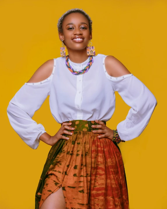 a woman standing in front of a yellow background, inspired by Chinwe Chukwuogo-Roy, trending on unsplash, dressed in long fluent skirt, prideful look, set against a white background, smiling confidently