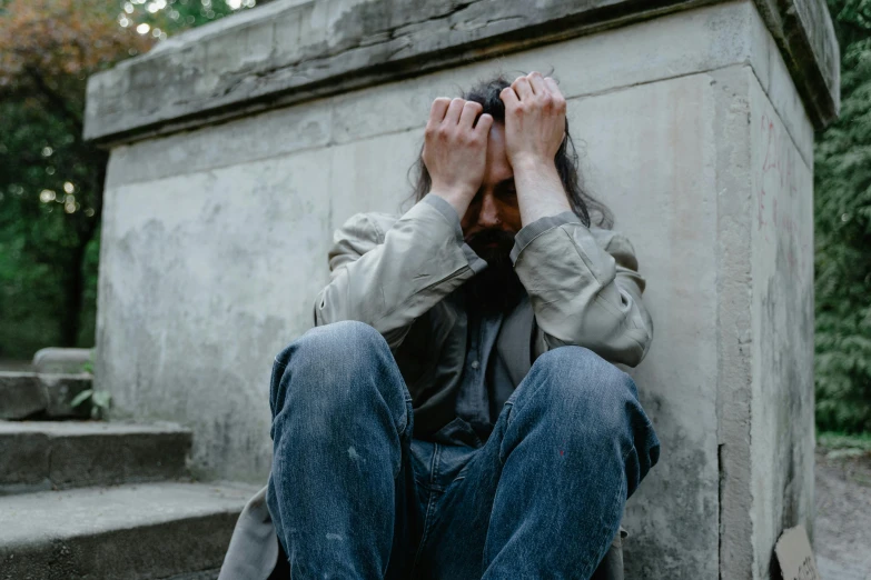 a man sitting on the ground covering his face with his hands, pexels, renaissance, background image, disheveled, distraught, grey