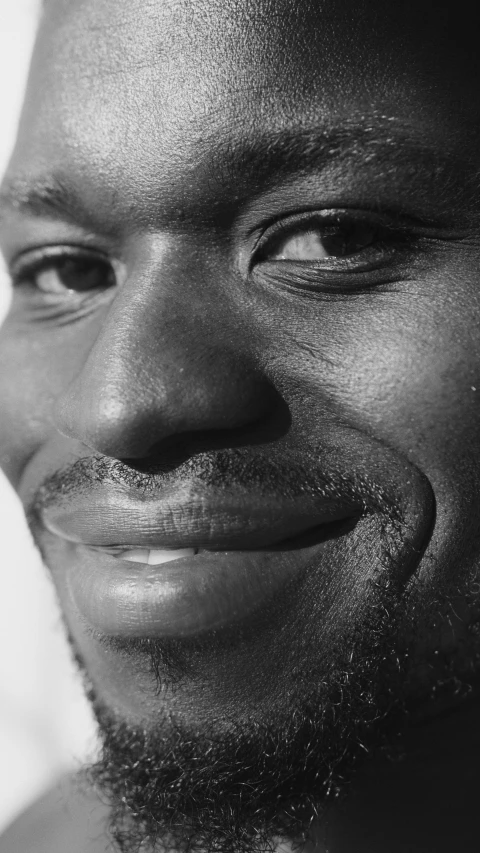 a black and white photo of a man smiling, inspired by Paul Georges, close - up profile, black man, 1999 photograph, high angle close up shot