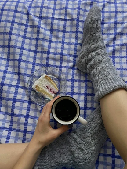 a person laying on a bed holding a cup of coffee, by Alice Mason, wearing kneesocks, having a picnic, grey and blue theme, gif