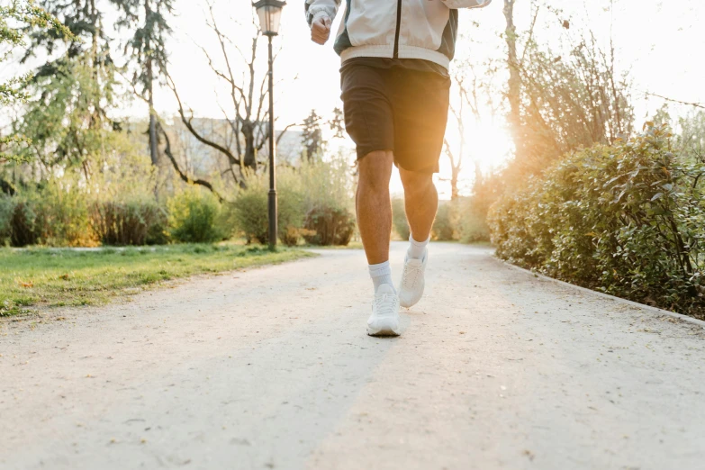 a man running down a path with trees in the background, pexels, happening, wearing white sneakers, morning sun, wearing shorts, avatar image