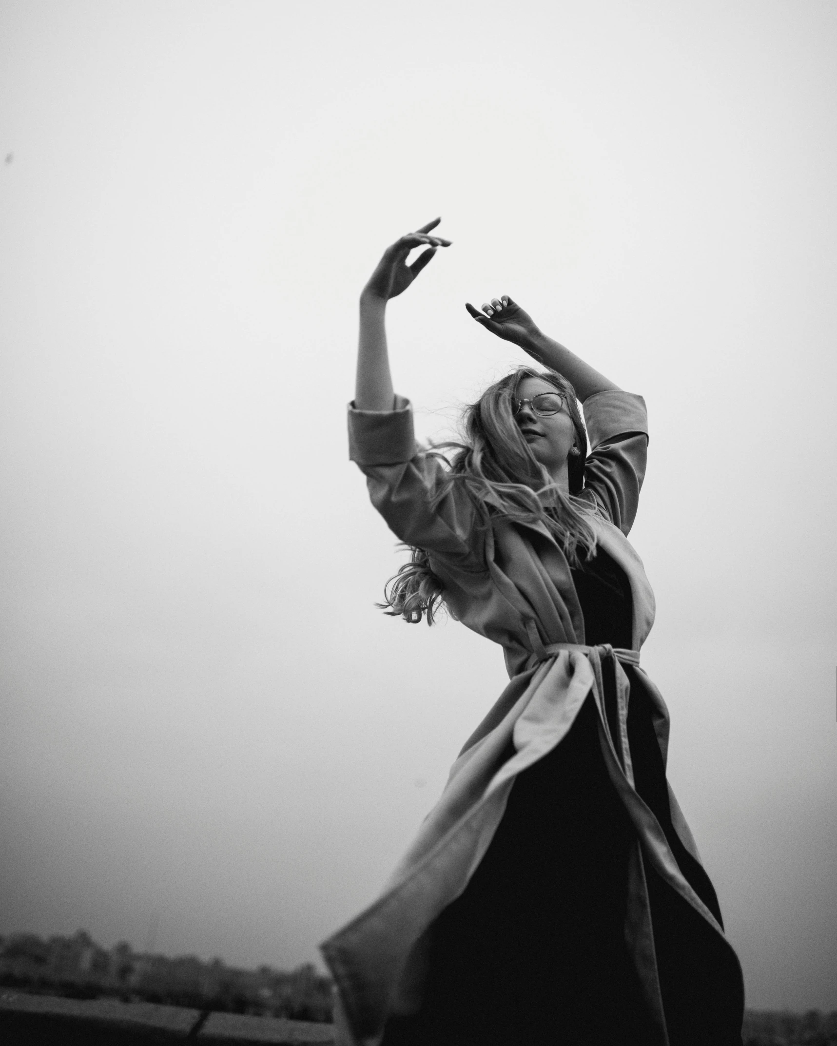 a black and white photo of a woman throwing a frisbee, a black and white photo, by Adam Marczyński, unsplash, renaissance, dancing in front of fog, girl in raincoat, doing a sassy pose, photography from vogue magazine