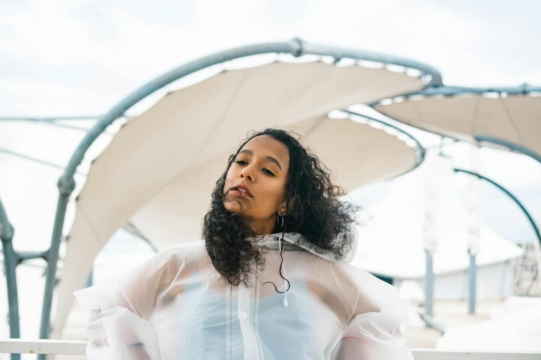 a woman sitting on top of a white bench, unsplash, afrofuturism, she is wearing a wet coat, wearing translucent sheet, on a boat, curls and curves