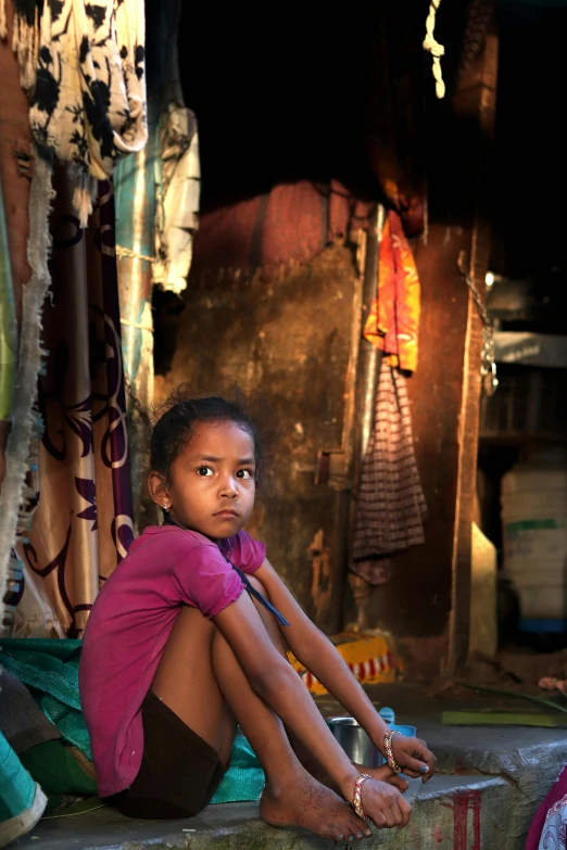 a little girl that is sitting on the ground, inspired by Steve McCurry, sumatraism, in a massive cavernous iron city, looking serious, dimly - lit, sweet home