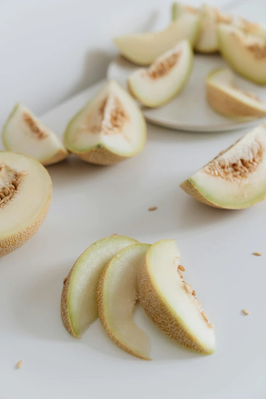 a white plate topped with slices of melon, a picture, inspired by Kanō Naizen, trending on pexels, renaissance, pear, beige, organic detail, 35 mm product photo”