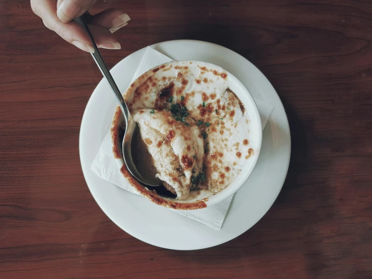 a person holding a spoon over a bowl of food, cappuccino, brown sauce, fan favorite, hot food