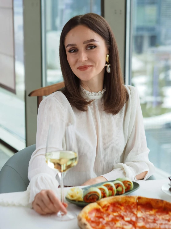 a woman sitting at a table with a pizza and a glass of wine, olga kurylenko, vp of marketing, hasbulla magomedov, portrait image