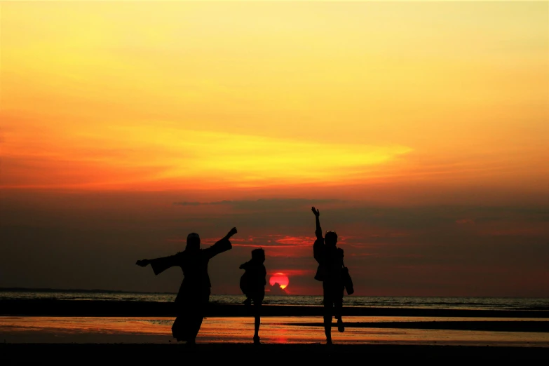 a group of people standing on top of a beach, by Sudip Roy, pexels contest winner, hurufiyya, flying through sunset, pregnancy, tai chi, the three suns