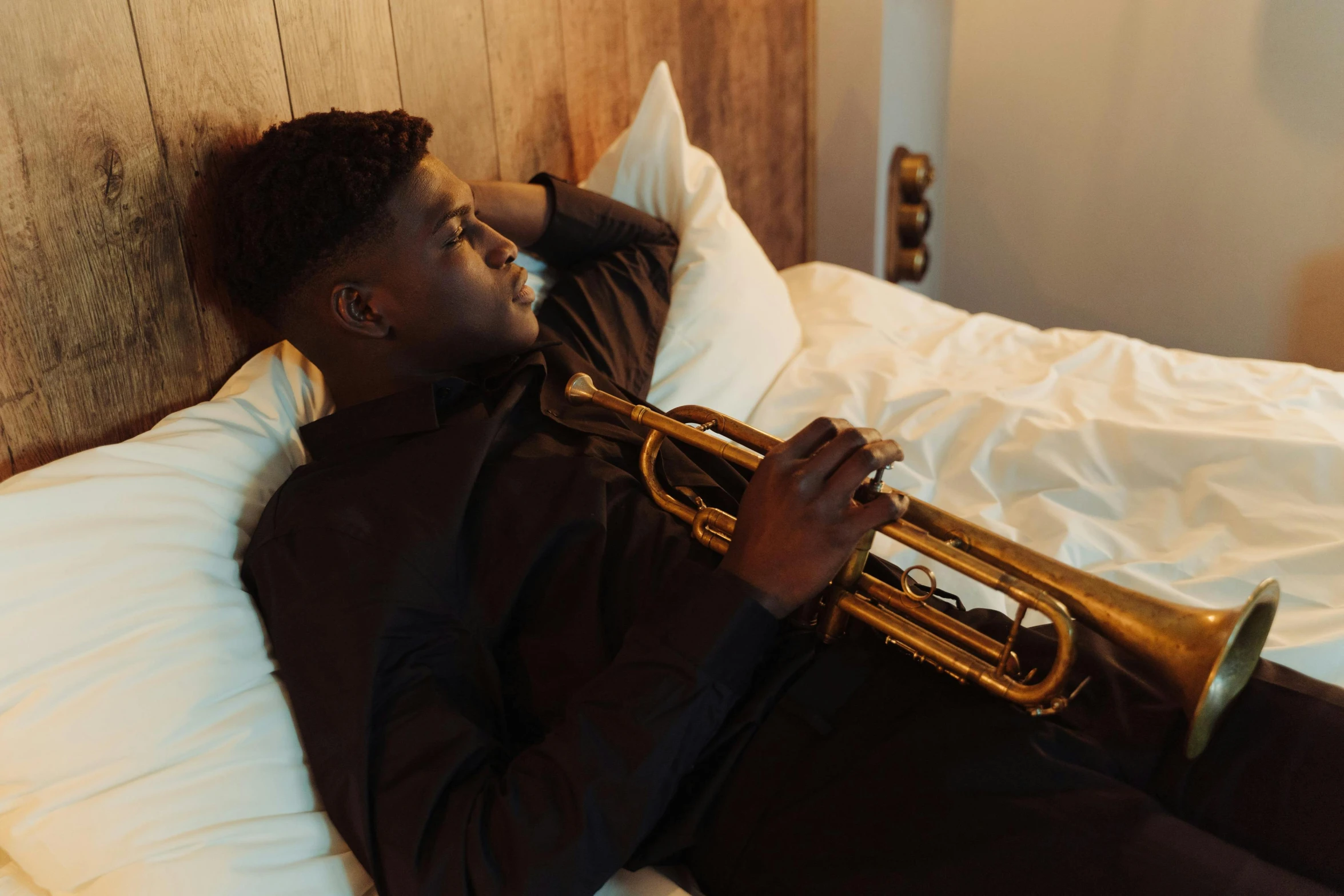 a man laying on a bed with a trumpet, by Sam Charles, pexels contest winner, hurufiyya, jaylen brown, profile image, sydney mortimer laurence, slightly turned to the right