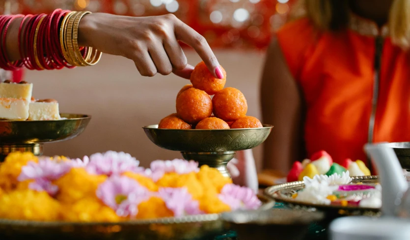 a close up of a plate of food on a table, hindu aesthetic, a woman holding an orb, vibrant orange, sweets